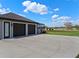 A three car garage and long concrete driveway with a serene landscape view at 15523 Trotting Horse Ln, Tavares, FL 32778