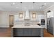 Modern kitchen featuring a large island, stainless steel appliances, and custom lighting at 15523 Trotting Horse Ln, Tavares, FL 32778