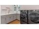 Well-lit laundry room with modern gray cabinets, sleek countertop, and stainless steel, front-loading washer and dryer at 15523 Trotting Horse Ln, Tavares, FL 32778