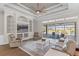Bright living room features a tray ceiling, modern fan, built-in shelving, and sliding doors to the pool area at 15523 Trotting Horse Ln, Tavares, FL 32778