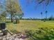 Spacious backyard with lush green grass and a playground set with golf course in the distance at 20604 Maxim Pkwy, Orlando, FL 32833