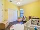 A cozy room with yellow walls, a window, alphabet rug, a rocking chair, and a white crib at 20604 Maxim Pkwy, Orlando, FL 32833
