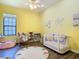 Bright and airy bedroom with yellow walls, a white crib, a play area and a ceiling fan at 20604 Maxim Pkwy, Orlando, FL 32833
