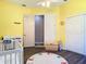 Cozy bedroom with yellow walls, alphabet rug, white closet doors, and gray adjoining room at 20604 Maxim Pkwy, Orlando, FL 32833