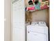 Laundry closet with white washer and dryer, with upper storage, next to a white door at 20604 Maxim Pkwy, Orlando, FL 32833