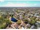 An aerial view features a pond nestled within a vibrant neighborhood with mature trees and well-maintained homes at 2112 White Eagle St, Clermont, FL 34714