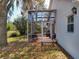 Exterior shot of screened in patio of home's backyard, with mature trees and landscaping at 2112 White Eagle St, Clermont, FL 34714