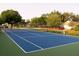 Community outdoor tennis court with blue surface, net and white lines surrounded by green foliage at 2112 White Eagle St, Clermont, FL 34714
