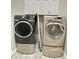 Modern laundry room with front-load washer and dryer with grey tile floors, and white cabinets at 307 Running Wind Ln, Maitland, FL 32751