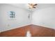 Bright bedroom features hardwood floors, two windows with shutters, and a ceiling fan at 33333 Somerset Dr, Leesburg, FL 34788