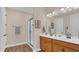 Modern bathroom featuring dual sinks, wood cabinets, a large mirror, and a glass enclosed shower at 4009 Swan Goose Ct, Okahumpka, FL 34762