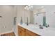 Bright bathroom featuring dual sinks, a large mirror, wood cabinets, and a shower with a glass door at 4009 Swan Goose Ct, Okahumpka, FL 34762