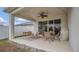 Cozy covered patio featuring a ceiling fan, outdoor dining set, and a striped outdoor rug at 4009 Swan Goose Ct, Okahumpka, FL 34762