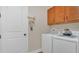 Clean laundry room featuring a white washer and dryer set, light wood cabinets, and a bright white door at 4009 Swan Goose Ct, Okahumpka, FL 34762