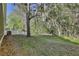 Backyard features mature trees, green space, and a partial fence at 604 Coral Trace Blvd, Edgewater, FL 32132
