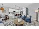 Open-concept living space showcasing a white kitchen, dining area, and stylish living room with blue armchairs at 730 Longboat Dr, Davenport, FL 33896