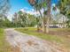 Charming one-story home featuring a gravel driveway and beautiful landscaping with mature palm trees and green lawn at 758 Osceola Dr, Sanford, FL 32773