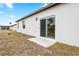 Backyard view features a white home exterior with a sliding glass door and windows under a blue sky at 833 S Hancock Dr, Deltona, FL 32725