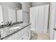 This bathroom features a granite countertop, white cabinets, and a bathtub with a shower at 1024 Green Gate Blvd, Groveland, FL 34736