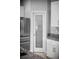 Close-up of stainless steel refrigerator and an adjacent pantry with decorative glass door and granite counters at 1024 Green Gate Blvd, Groveland, FL 34736