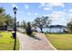 Beautifully landscaped walking path leading to a tranquil lakeside area with benches and shaded seating at 1024 Green Gate Blvd, Groveland, FL 34736