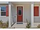 A welcoming red front door with glass and white trim, flanked by red shutters and fresh plants at 11356 Sunsail Ave, Orlando, FL 32832