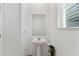 Simple and efficient powder room with a pedestal sink, mirror, and natural light from the window at 11356 Sunsail Ave, Orlando, FL 32832