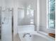 Elegant main bathroom showcasing a soaking tub, separate shower, and large window, with natural light at 11537 Claymont Cir, Windermere, FL 34786