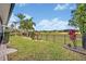 Landscaped backyard with lush green grass, tropical plants, dark metal fence bordering the community golf course at 13067 Woodford St, Orlando, FL 32832
