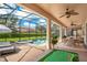 Outdoor patio with a covered dining area, putting green, and a screened-in pool and spa at 1445 Rolling Fairway Dr, Davenport, FL 33896