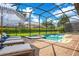 Enclosed outdoor pool area with lounge chairs, spa, and lush green surroundings at 1445 Rolling Fairway Dr, Davenport, FL 33896