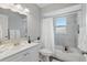 Bright bathroom featuring a tub with white marble-style tile, a shower, and a white vanity with sink at 1612 Eastbrook Blvd, Winter Park, FL 32792