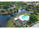 Aerial view of community pool with sun loungers, palm trees, and bridge over calm lake at 164 Reserve Cir # 208, Oviedo, FL 32765