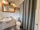 Tiled bathroom featuring a sink, medicine cabinet, toilet and gray shower curtain with wood accents at 202 S Hampton Ave, Orlando, FL 32803