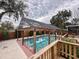 Backyard pool with a screened enclosure and wooden supports, surrounded by trees and privacy fence at 202 S Hampton Ave, Orlando, FL 32803