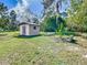 A backyard shed sits on a well-manicured lawn, surrounded by green vegetation at 2411 Crawford Dr, Sanford, FL 32771