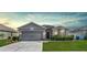 Inviting single-Gathering home with a well-maintained lawn, attached garage, and stylish exterior lighting at 3086 Brenton Manor Loop, Winter Haven, FL 33881