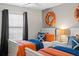 Nautical-themed bedroom featuring two twin beds, each adorned with vibrant orange and blue bedding at 4895 Clock Tower Dr, Kissimmee, FL 34746