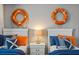 Charming bedroom featuring two twin beds adorned with nautical-themed decor and bright orange and blue accents at 4895 Clock Tower Dr, Kissimmee, FL 34746