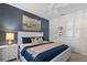 Stylish bedroom with a comfortable bed, white dresser, and abstract art against a dark blue accent wall at 4895 Clock Tower Dr, Kissimmee, FL 34746