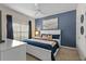 This bedroom features a large window, a plush bed, and a soothing dark blue accent wall at 4895 Clock Tower Dr, Kissimmee, FL 34746