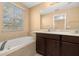 Spacious bathroom featuring a double vanity with quartz counters, dark wood cabinets, and a large tub at 5252 Hidden Cypress Ln, Oviedo, FL 32765