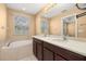 Large bathroom vanity with double sinks, dark brown cabinets, and a window overlooking the bathtub at 5252 Hidden Cypress Ln, Oviedo, FL 32765