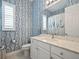 Bright bathroom featuring a white vanity with a marble countertop and patterned blue wallpaper at 8400 Bridgeport Bay Cir, Mount Dora, FL 32757