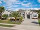 Charming single-story home featuring a brick-paved driveway, well-manicured lawn, and beautiful landscaping at 8400 Bridgeport Bay Cir, Mount Dora, FL 32757