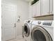 Well-equipped laundry room with modern appliances and overhead cabinets at 8400 Bridgeport Bay Cir, Mount Dora, FL 32757