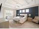 Spacious main bedroom with a patterned accent wall, coffered ceiling, and seating area near a bright window at 8400 Bridgeport Bay Cir, Mount Dora, FL 32757