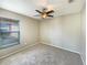 Neutral bedroom features plush carpet, ceiling fan, and a window providing natural light at 8603 Primrose Dr, Kissimmee, FL 34747