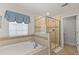 Bright bathroom boasts tiled shower, a soaking tub, and a window with blue valance at 9023 Shadow Mountain St, Davenport, FL 33896