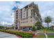 Beautiful condo building with awnings, palm trees, manicured lawn, and blue skies at 111 E Monument Ave # 705, Kissimmee, FL 34741